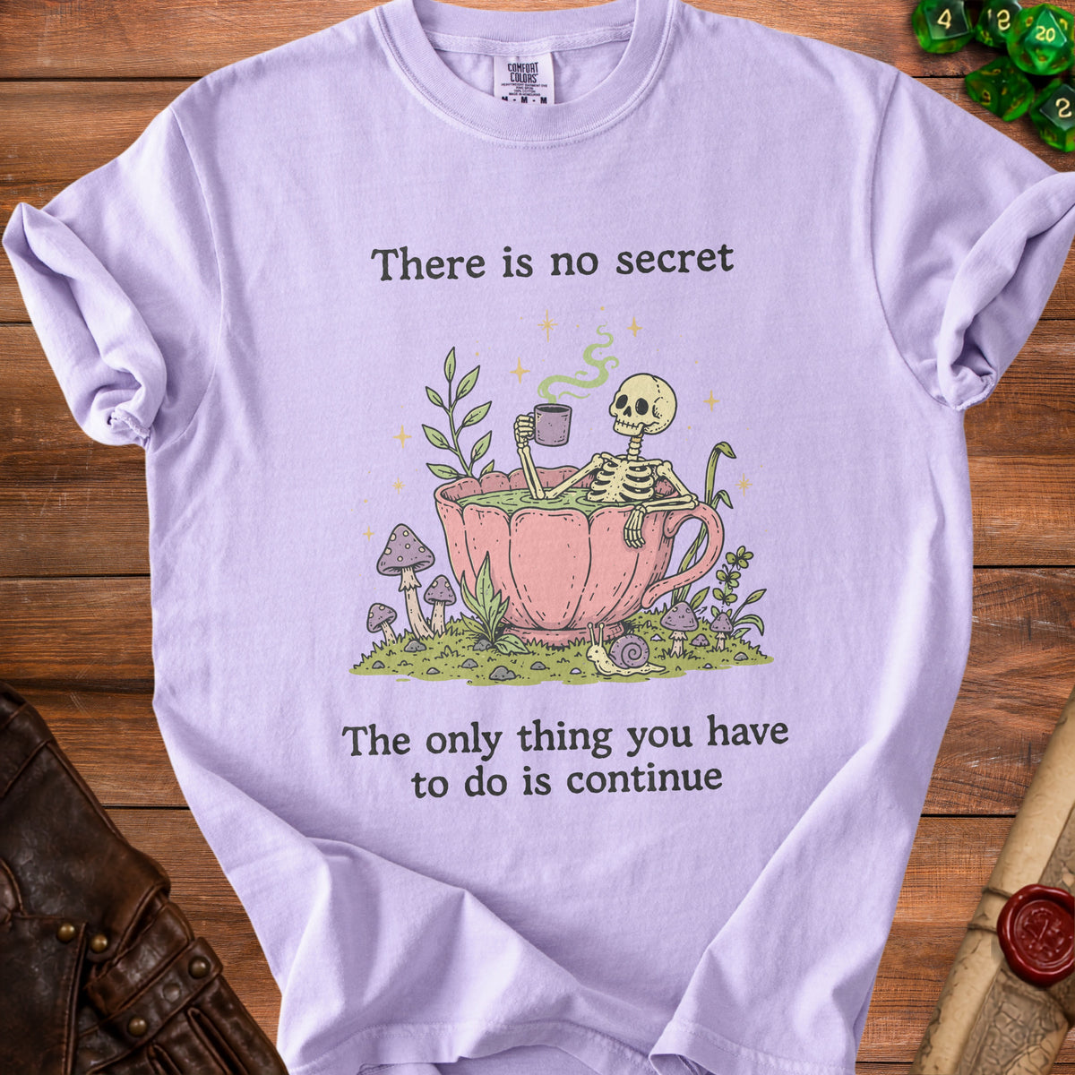 Lavender t-shirt with skeleton in teacup graphic and text "There is no secret, The only thing you have to do is continue."