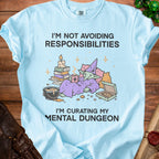 Light blue t-shirt with a goblin character and the text "I'm not avoiding responsibilities, I'm curating my mental dungeon."