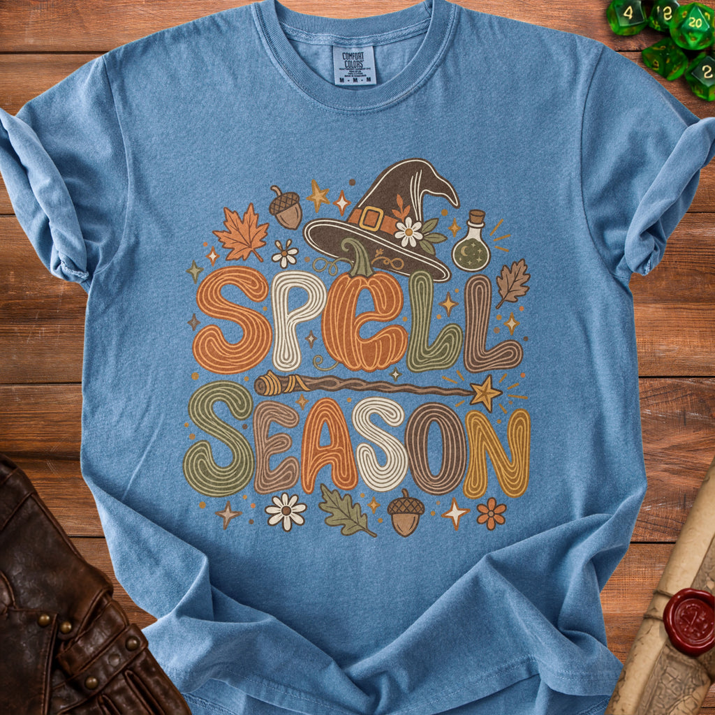 Blue t-shirt with "SPELL SEASON" text in decorative font, witch hat, and fall accents.