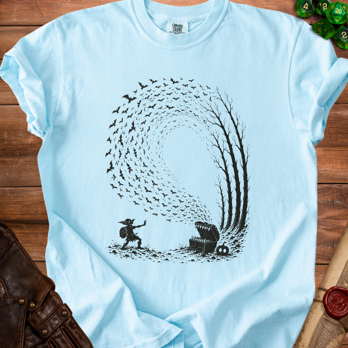 Light blue t-shirt with graphic of goblin, treasure chest, and bats.