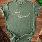 Green t-shirt with "Just Attuned" and "emotionally attached to questionable artifacts" text.