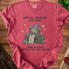 Red t-shirt with illustration of tired goblin wizard and text "Not All Quests Are Epic, Some Are Just Getting Through Tuesday".