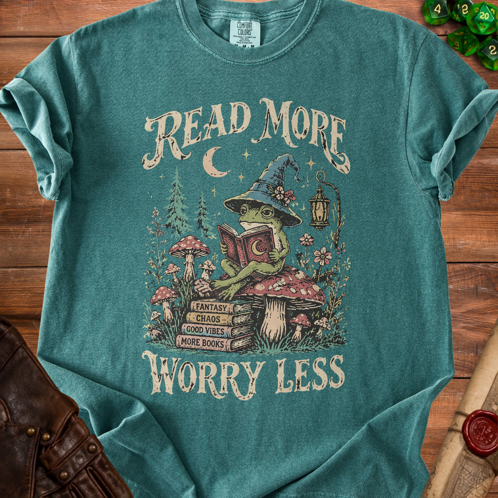 T-shirt with graphic of frog reading book, mushrooms, and text "Read More Worry Less".