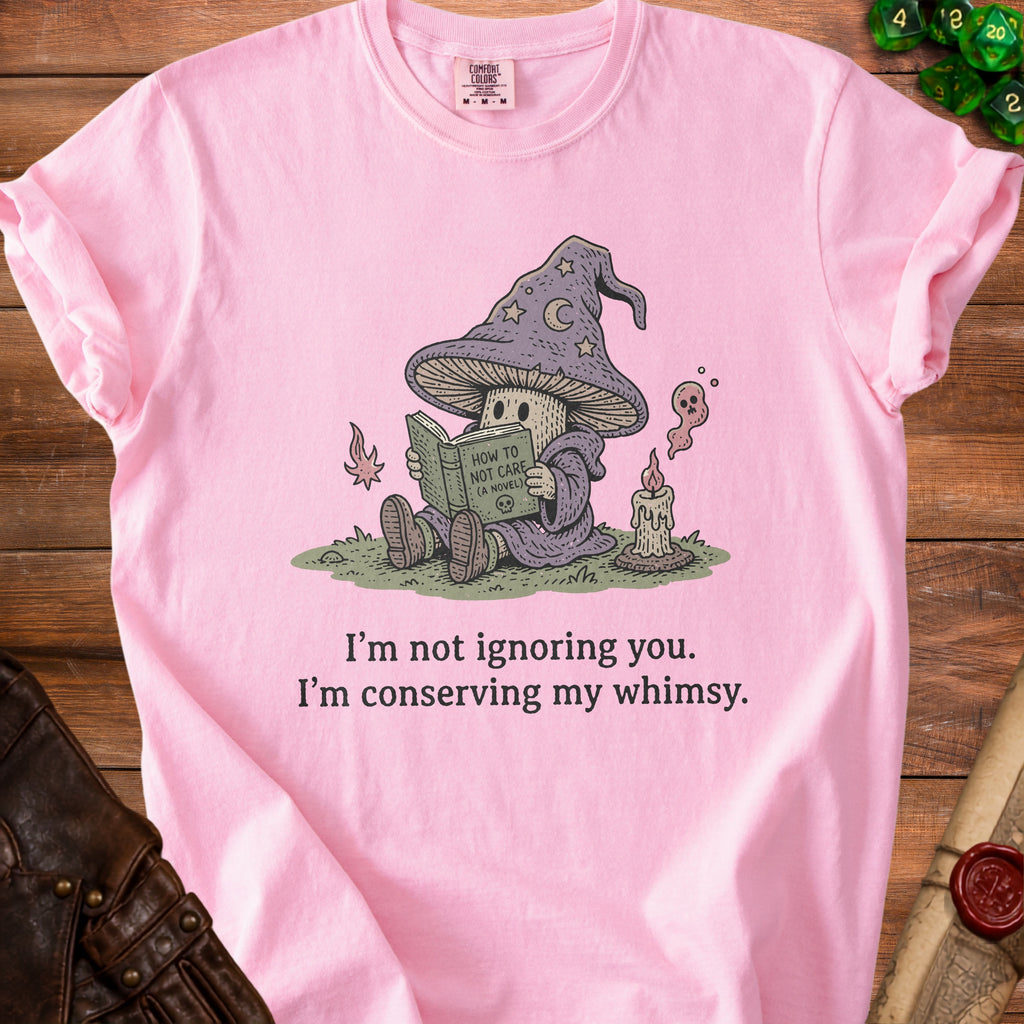 Pink t-shirt with graphic of a mushroom wizard reading "How to Not Care (A Novel)".