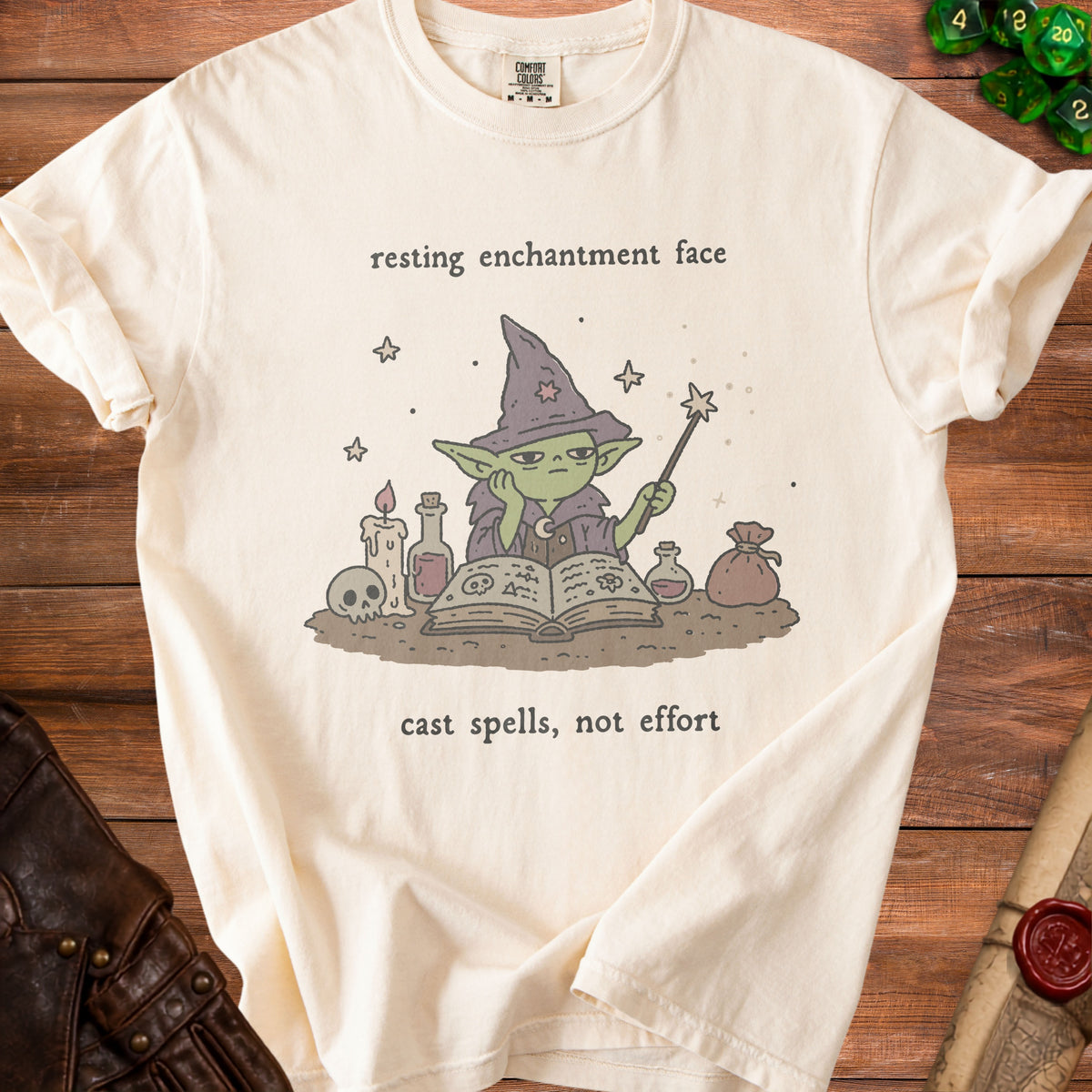 Cream t-shirt with graphic of a bored goblin wizard, "resting enchantment face" and "cast spells, not effort".