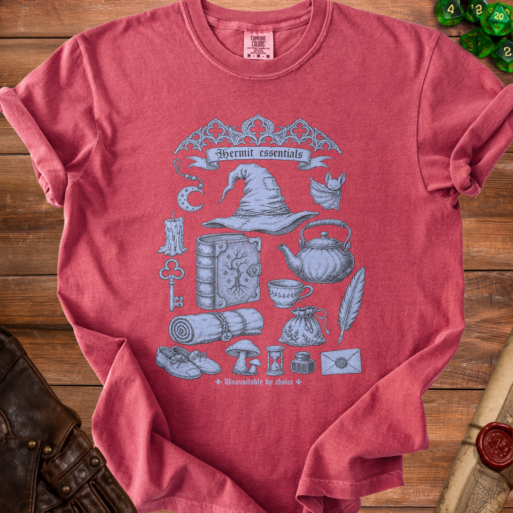 Red t-shirt with "Hermit essentials" and illustrations of magical items, a witch hat, and a bat.