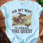 Light blue t-shirt with frog wizard holding a sword and text "ON MY WAY TO DERAIL THE QUEST".