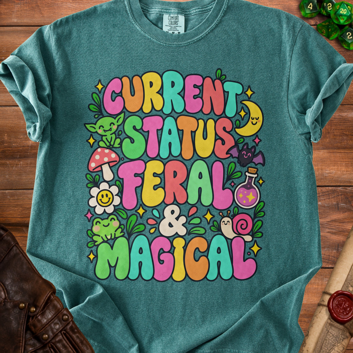 Teal t-shirt with "Current Status Feral & Magical" text and whimsical illustrations.