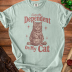 Light teal t-shirt with cat, dice, and text that reads "Critically Dependent On My Cat".