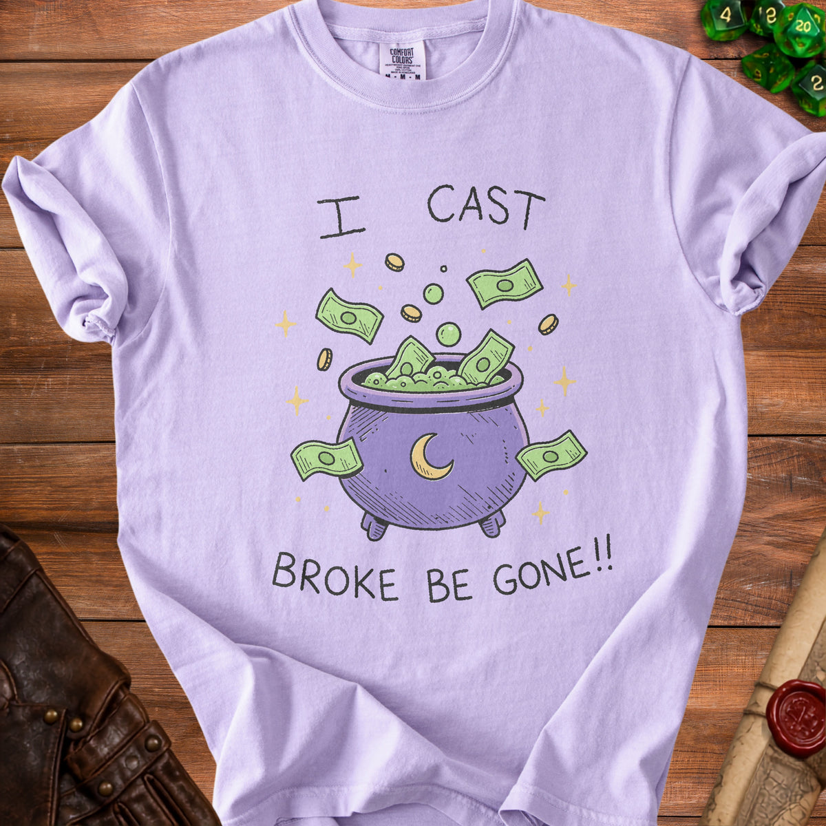 Lilac t-shirt with a cauldron overflowing with money, saying "I cast broke be gone!!"