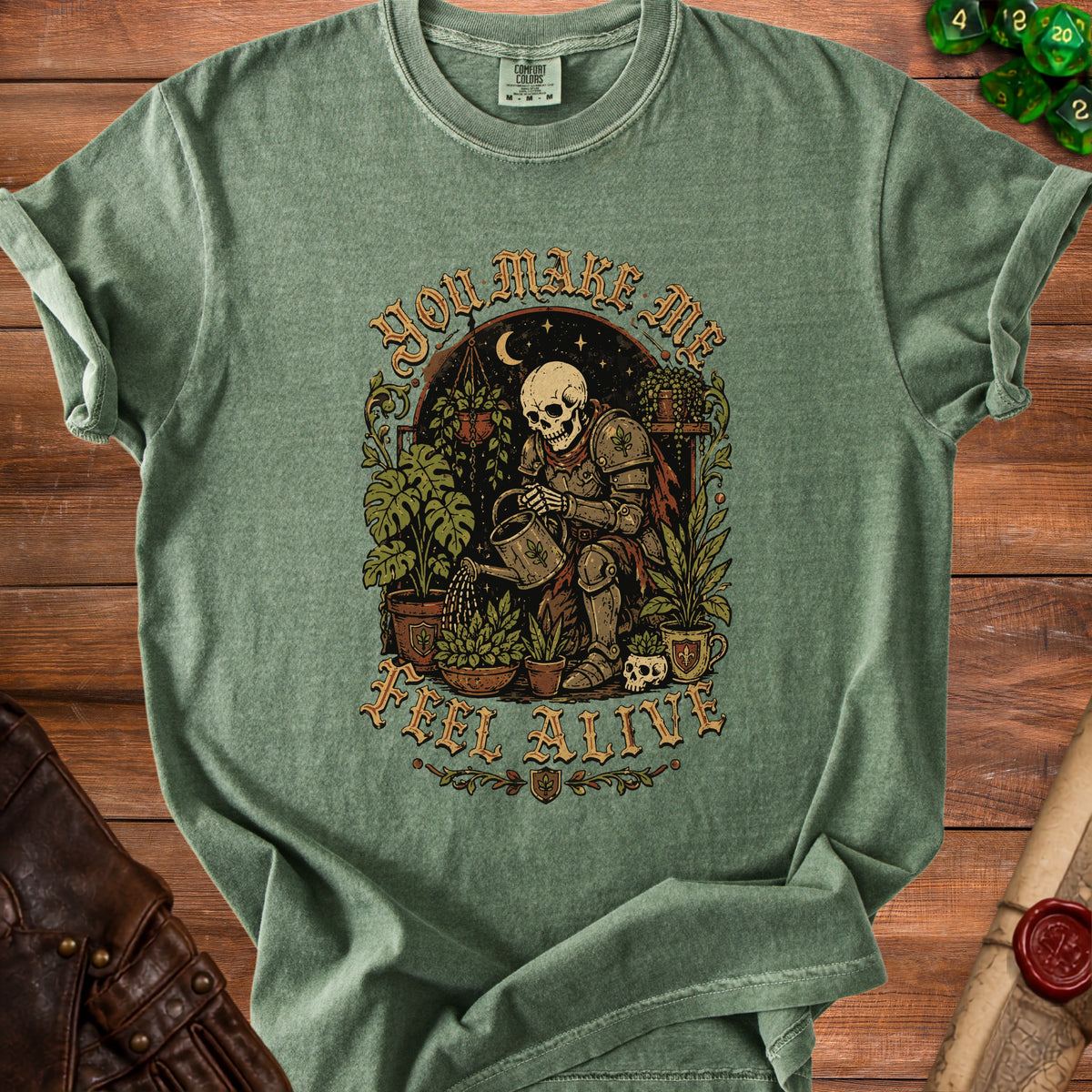 Green t-shirt with skeleton gardening graphic and "You Make Me Feel Alive" text.