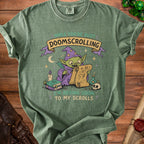 Green t-shirt graphic of a wizard goblin writing "I'm adding doom to my scrolls".