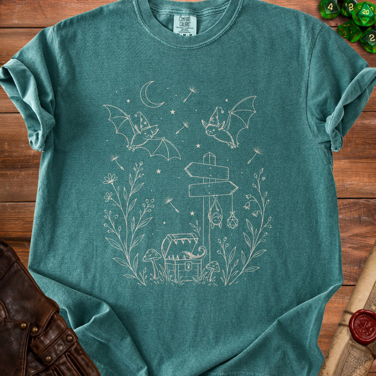 Teal t-shirt with line art of bats, chest, mushrooms, and celestial elements.