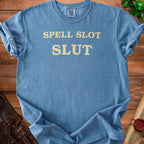 Blue t-shirt with yellow text "SPELL SLOT SLUT" and a Comfort Colors tag.