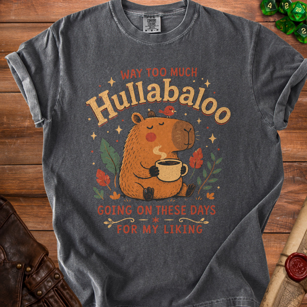 Dark gray t-shirt with a capybara graphic and text "WAY TOO MUCH Hullabaloo GOING ON THESE DAYS FOR MY LIKING".