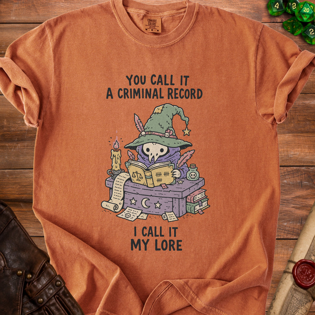 Orange t-shirt with illustration of a skull in a witch hat reading a book.