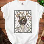 White t-shirt with a graphic of a raccoon, d20 die, and text "PANIC IS A FREE ACTION".