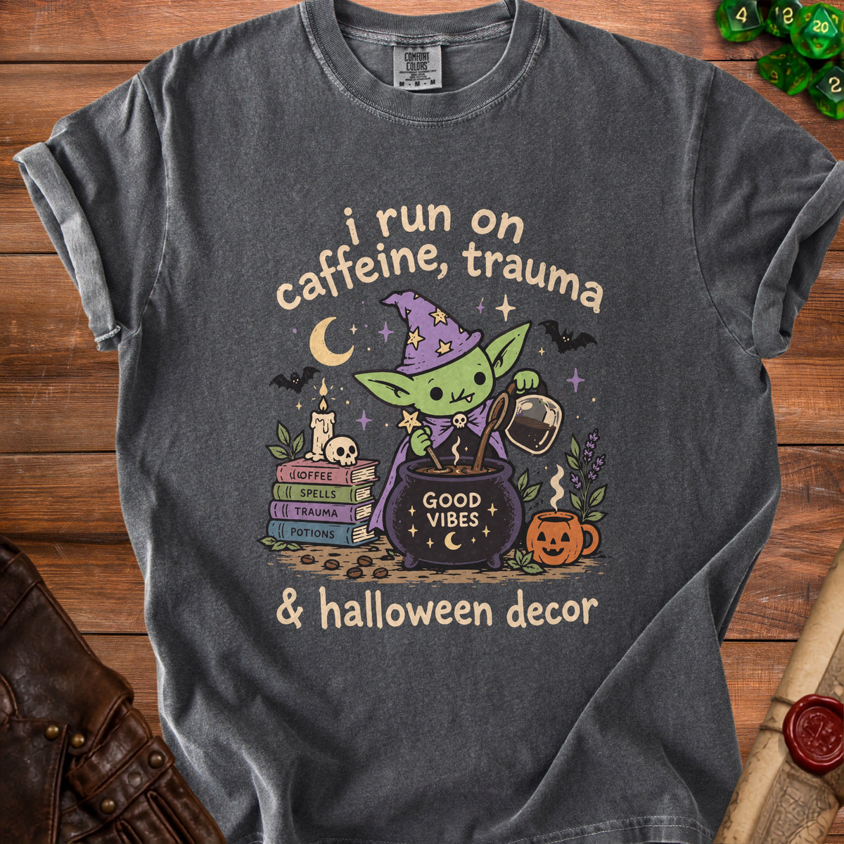 T-shirt graphic of a witchy goblin brewing coffee with text "i run on caffeine, trauma & halloween decor."