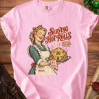 Pink t-shirt with a retro illustration of a woman serving a D20 dice labeled "Serving Hot Rolls".