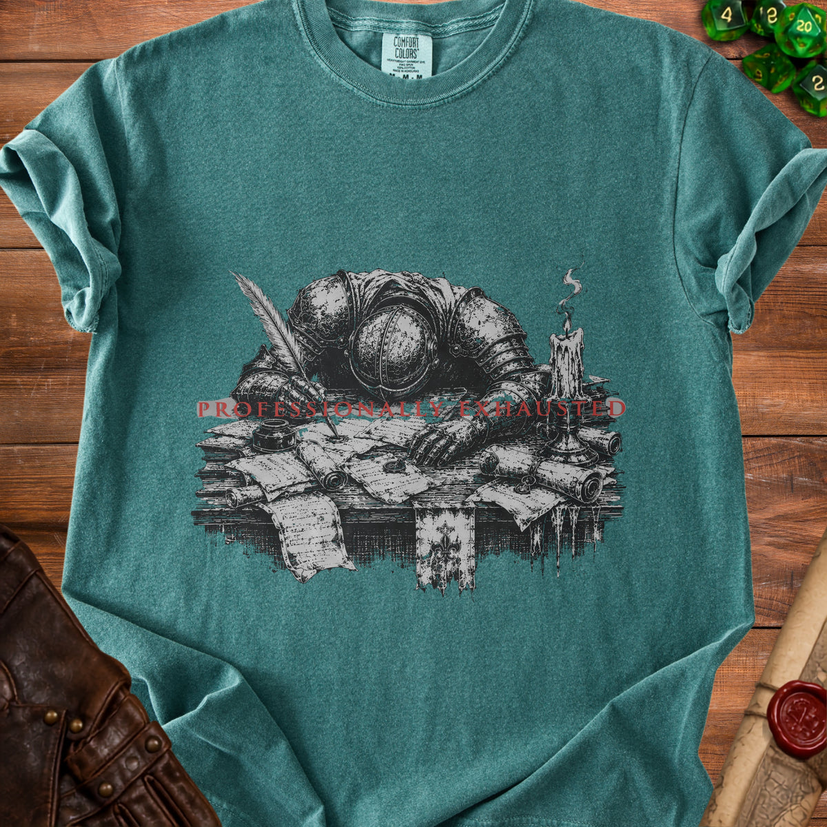 T-shirt graphic of knight in armor resting head on papers with quill and candle.