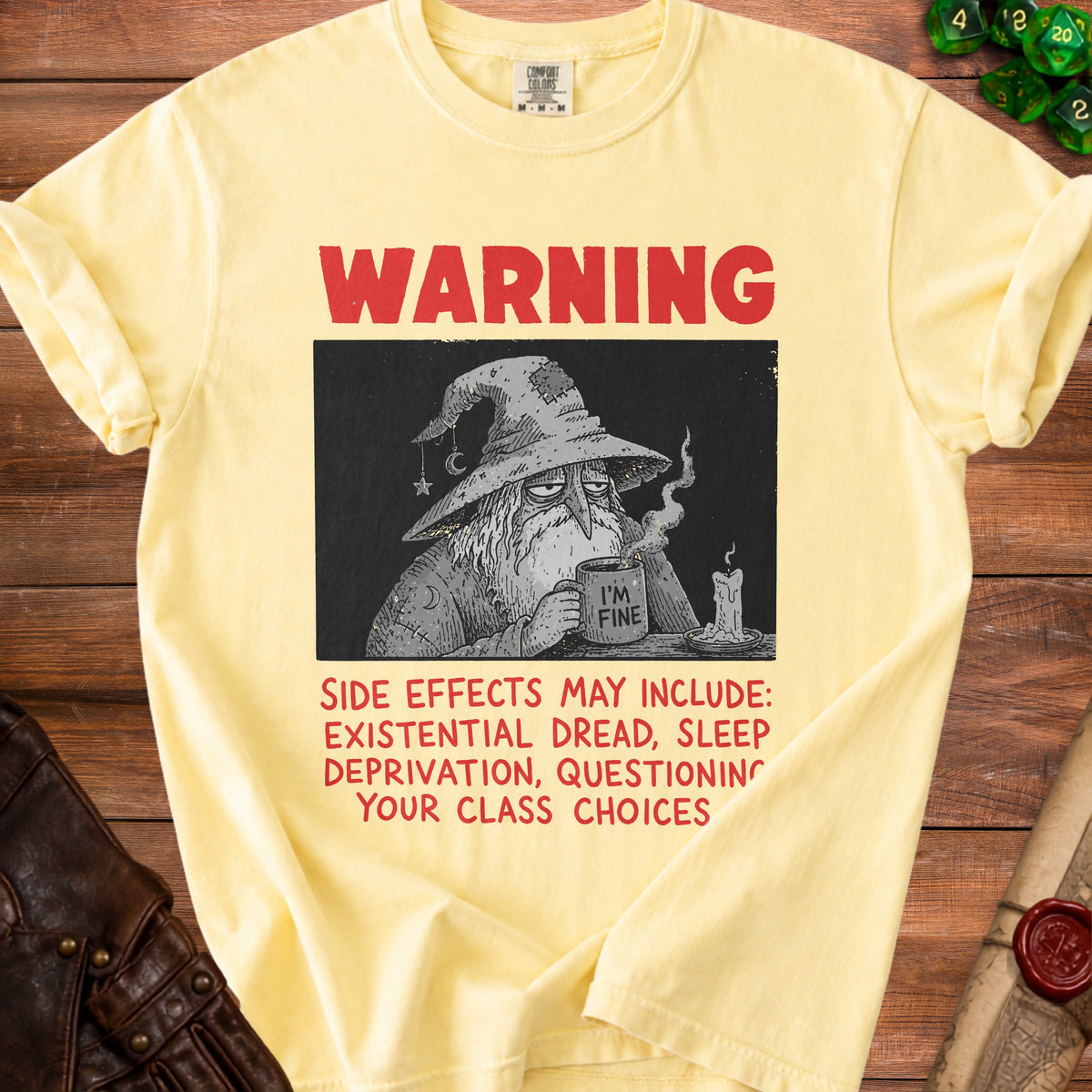 Yellow t-shirt with a wizard graphic and text "WARNING: SIDE EFFECTS MAY INCLUDE: EXISTENTIAL DREAD, SLEEP DEPRIVATION, QUESTIONING YOUR CLASS CHOICES".
