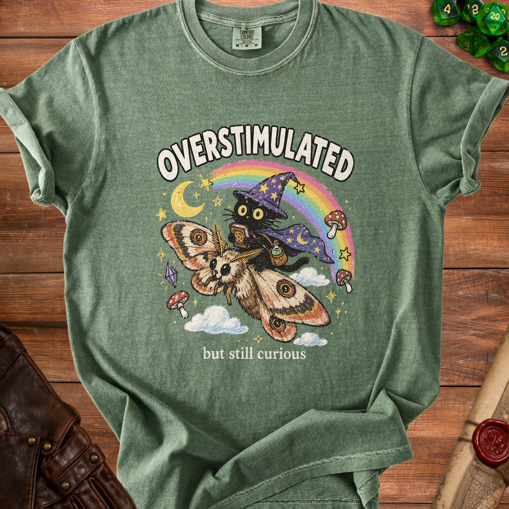 Green t-shirt with black cat riding a moth with text "OVERSTIMULATED but still curious".
