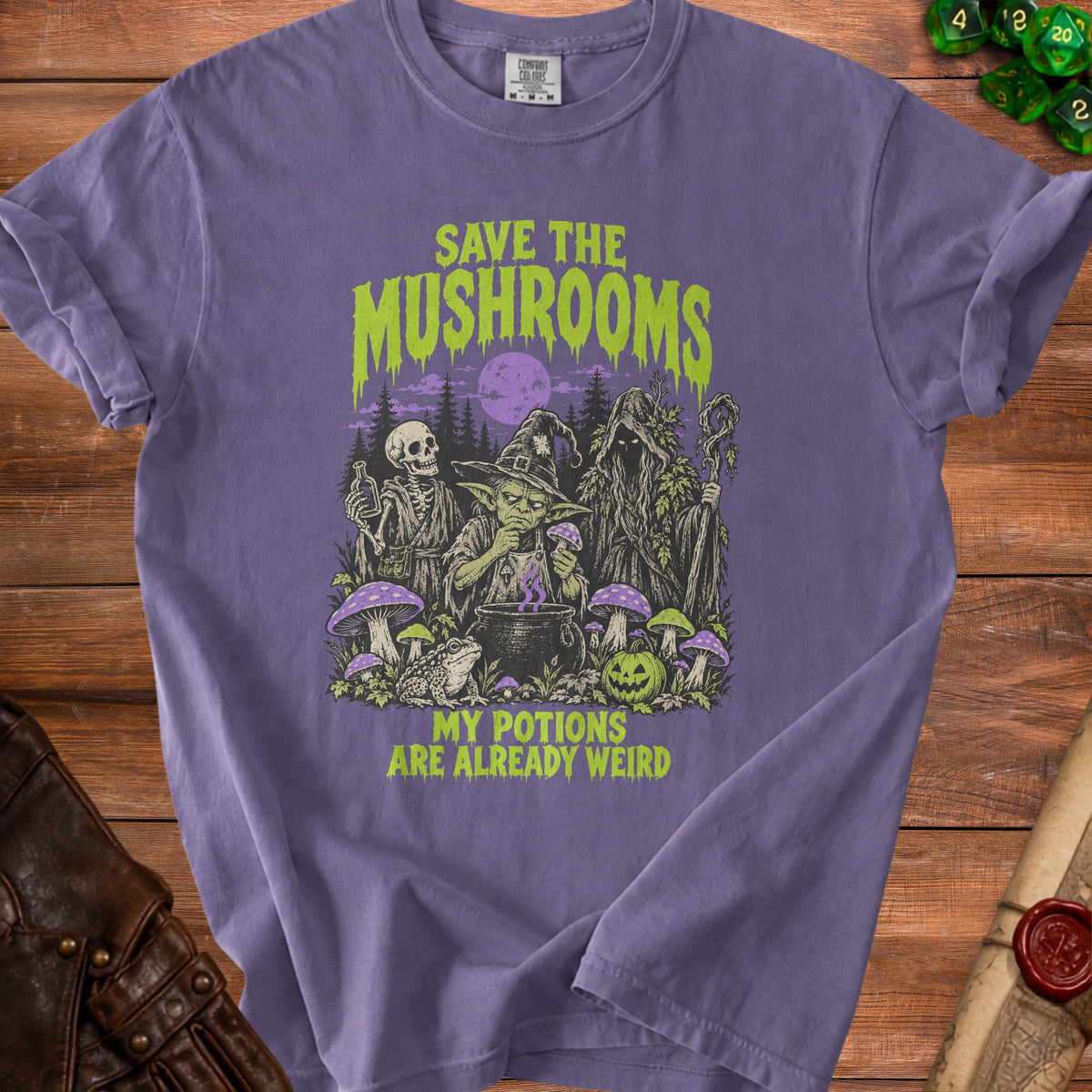 Purple t-shirt with goblins, skeleton, and mossy figure in forest with mushrooms. Text says "SAVE THE MUSHROOMS MY POTIONS ARE ALREADY WEIRD".
