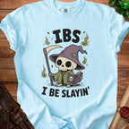 Light blue t-shirt with cartoon grim reaper reading a book and text "IBS I BE SLAYIN'".
