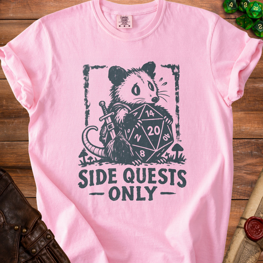 Pink t-shirt with a charcoal graphic of a possum holding a twenty-sided die and sword.