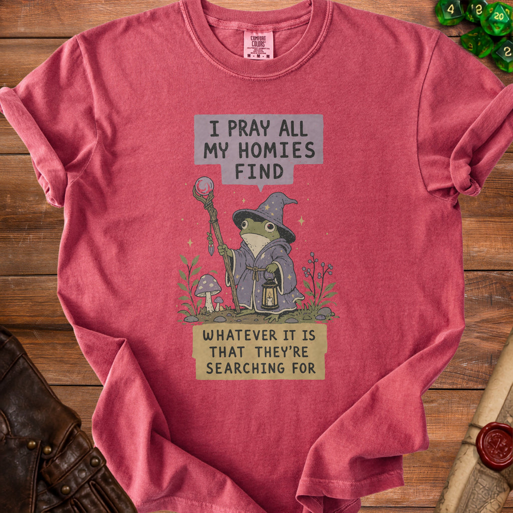 Red t-shirt with graphic of wizard frog holding staff and lantern, text reads "I pray all my homies find whatever it is that they're searching for".