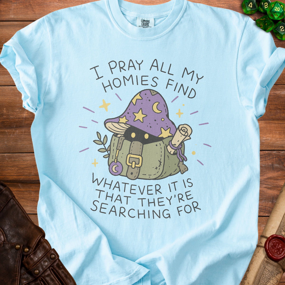Light blue Comfort Colors shirt with a graphic of a mushroom wizard and the text "I PRAY ALL MY HOMIES FIND WHATEVER IT IS THAT THEY'RE SEARCHING FOR".