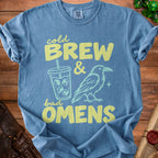 Blue t-shirt with yellow text "cold BREW & bad OMENS" and graphics.
