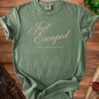 A green t-shirt with pink cursive text reading Just Escaped from an entirely optional gathering.