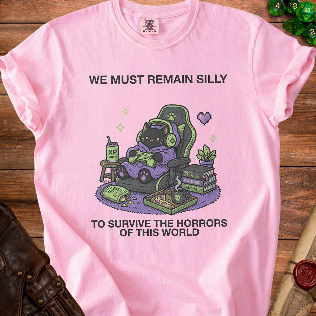 Pink t-shirt with graphic of cat gamer saying "We must remain silly to survive the horrors of this world."