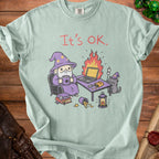 Light green t-shirt with wizard, cat, burning laptop, and "It's OK." text.