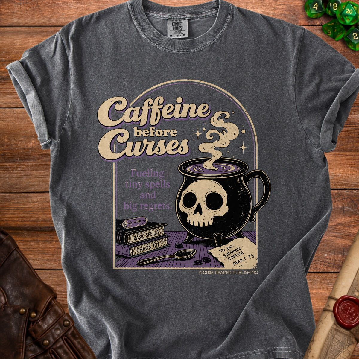 Dark grey t-shirt with "Caffeine before Curses" design, skull coffee mug, and spell books.