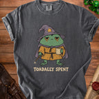 Charcoal t-shirt with graphic of tired frog wizard holding coffee and wand. Text says "TOADALLY SPENT".