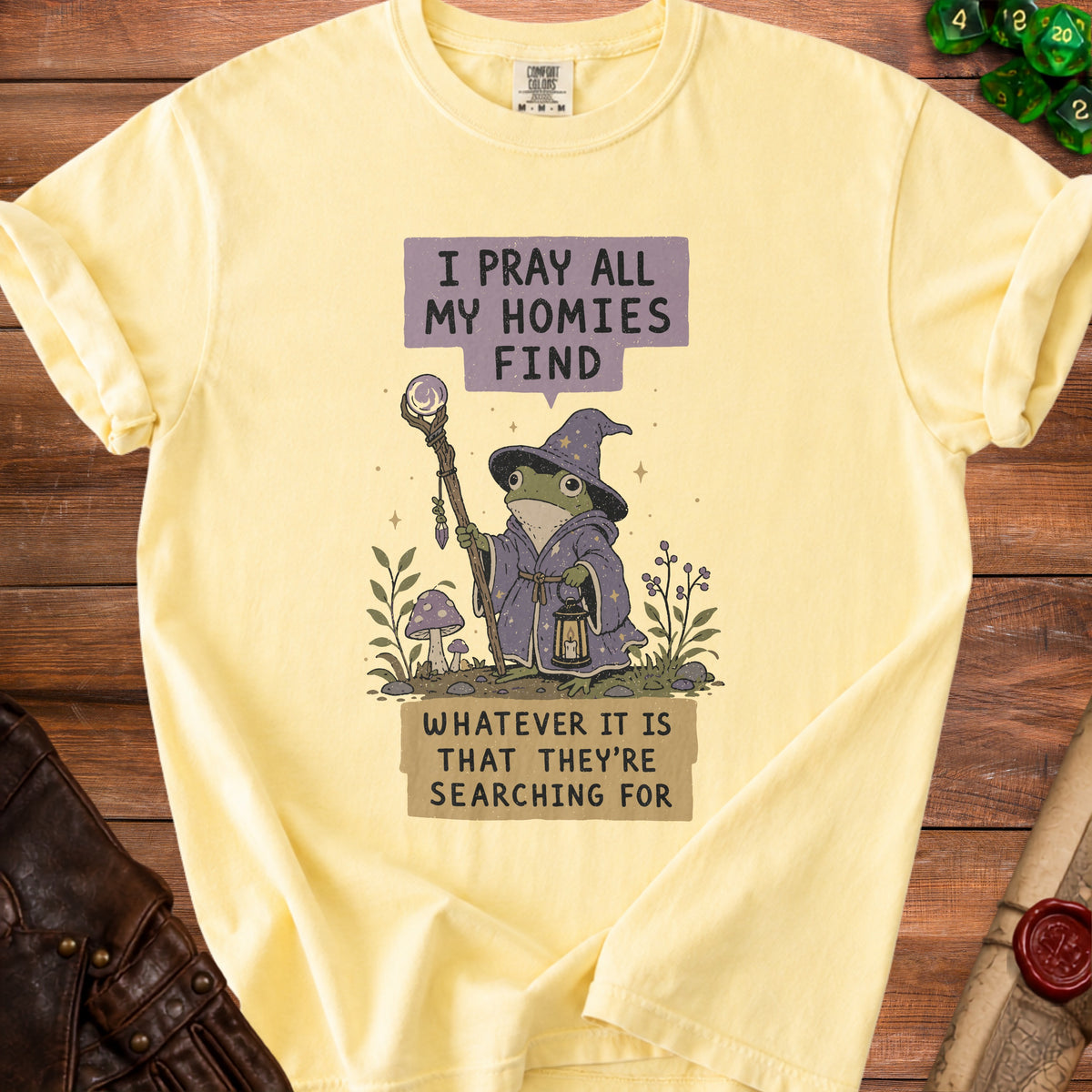 Light yellow t-shirt with frog wizard graphic and text "I pray all my homies find whatever it is that they're searching for."