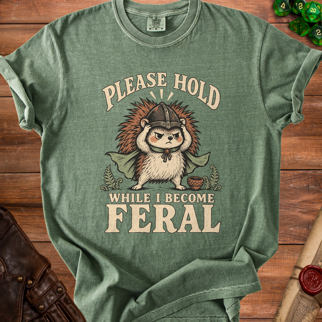 Green t-shirt with hedgehog in helmet and text "Please Hold While I Become Feral".