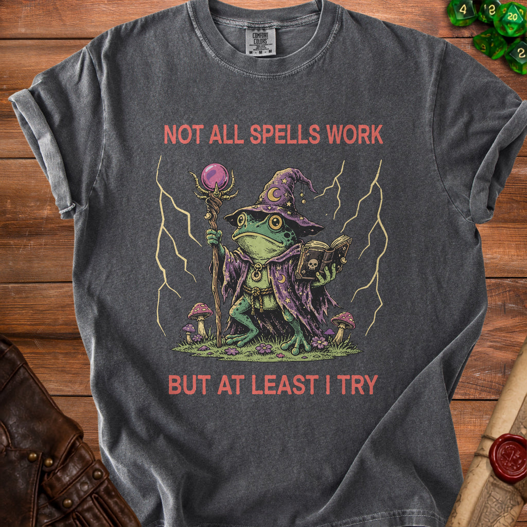 Dark gray t-shirt with wizard frog graphic and text "NOT ALL SPELLS WORK BUT AT LEAST I TRY".