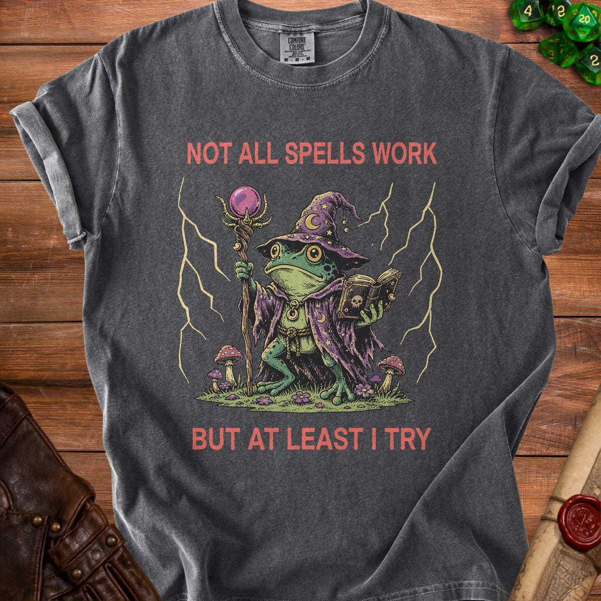 Dark gray t-shirt with wizard frog graphic and text "NOT ALL SPELLS WORK BUT AT LEAST I TRY".