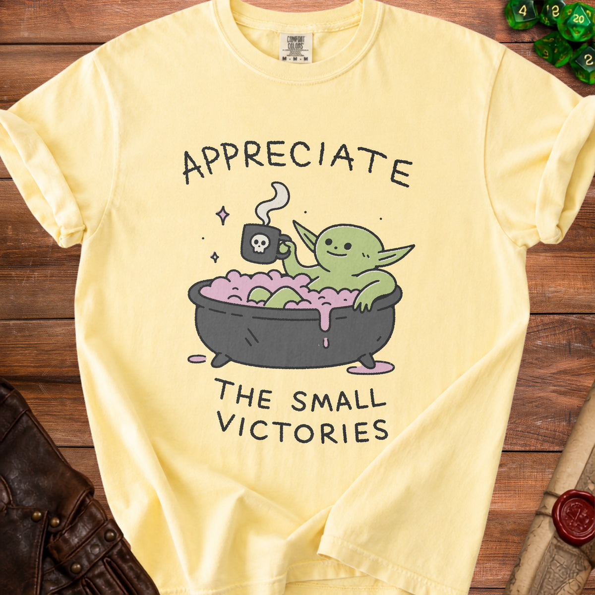 Yellow t-shirt with Yoda-like character in bathtub holding skull mug. Text reads "APPRECIATE THE SMALL VICTORIES".