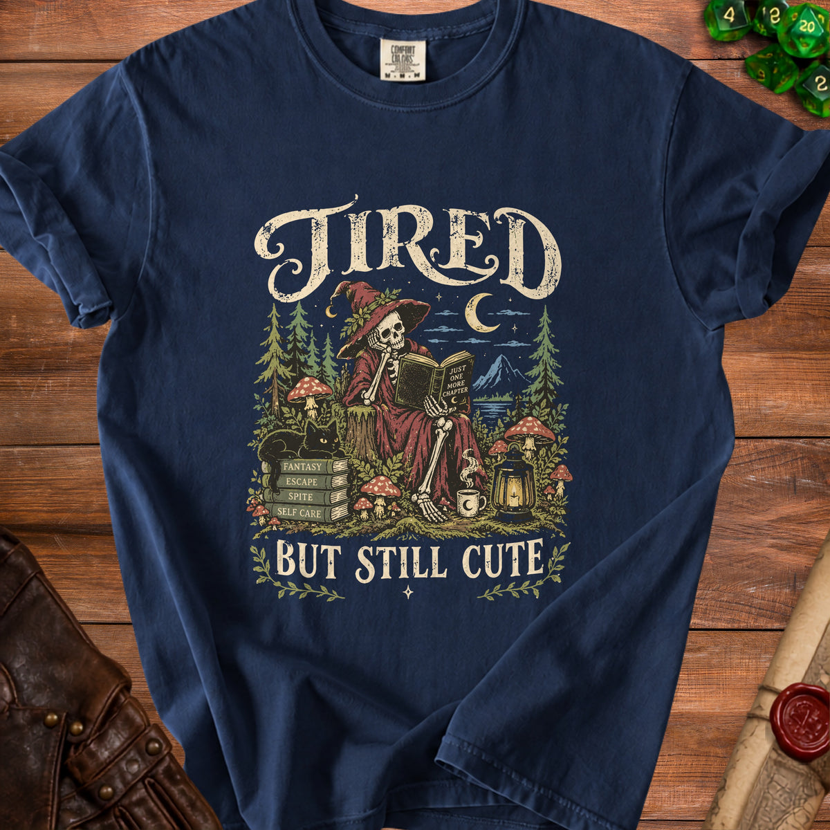 Dark blue t-shirt with skeleton witch reading, "Tired But Still Cute" text.