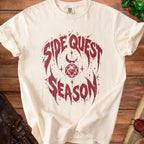 Cream t-shirt with maroon "Side Quest Season" graphic and D20 die.