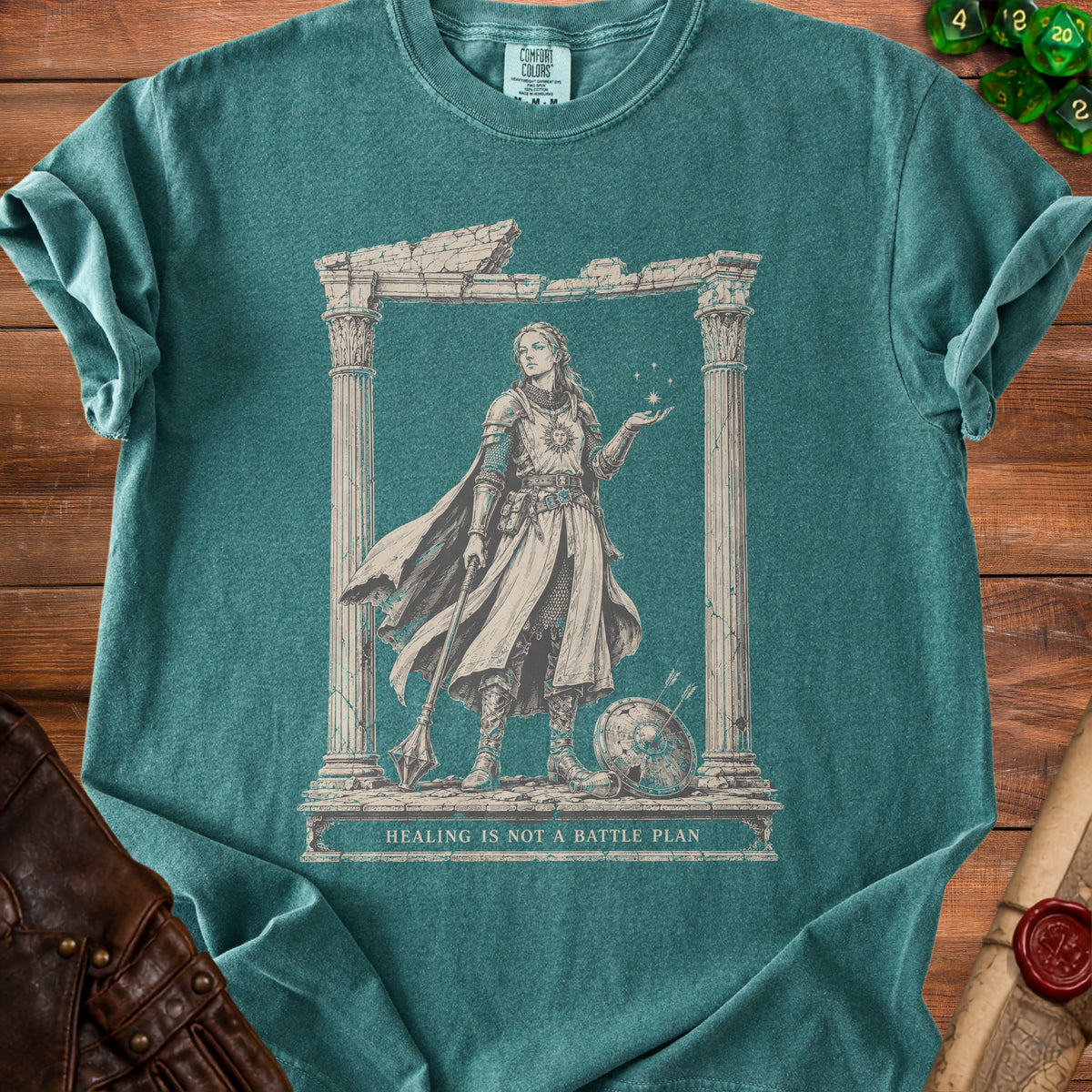 T-shirt graphic of a warrior woman within ancient ruins, holding stars. Text reads "HEALING IS NOT A BATTLE PLAN".