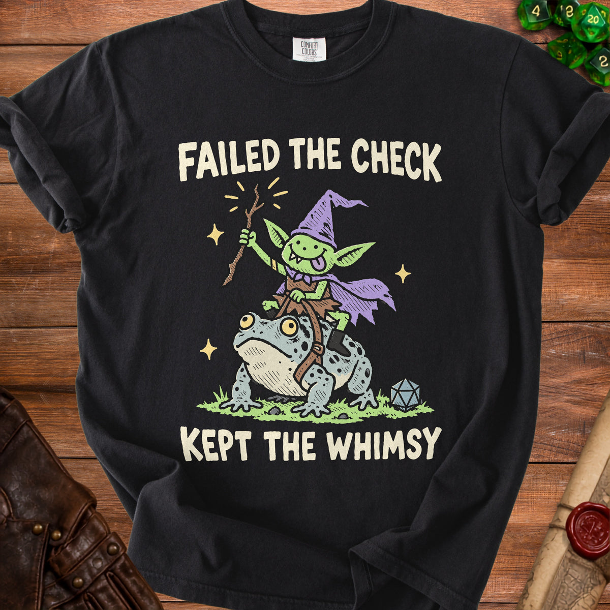 Black t-shirt with a goblin riding a frog and text "FAILED THE CHECK KEPT THE WHIMSY".