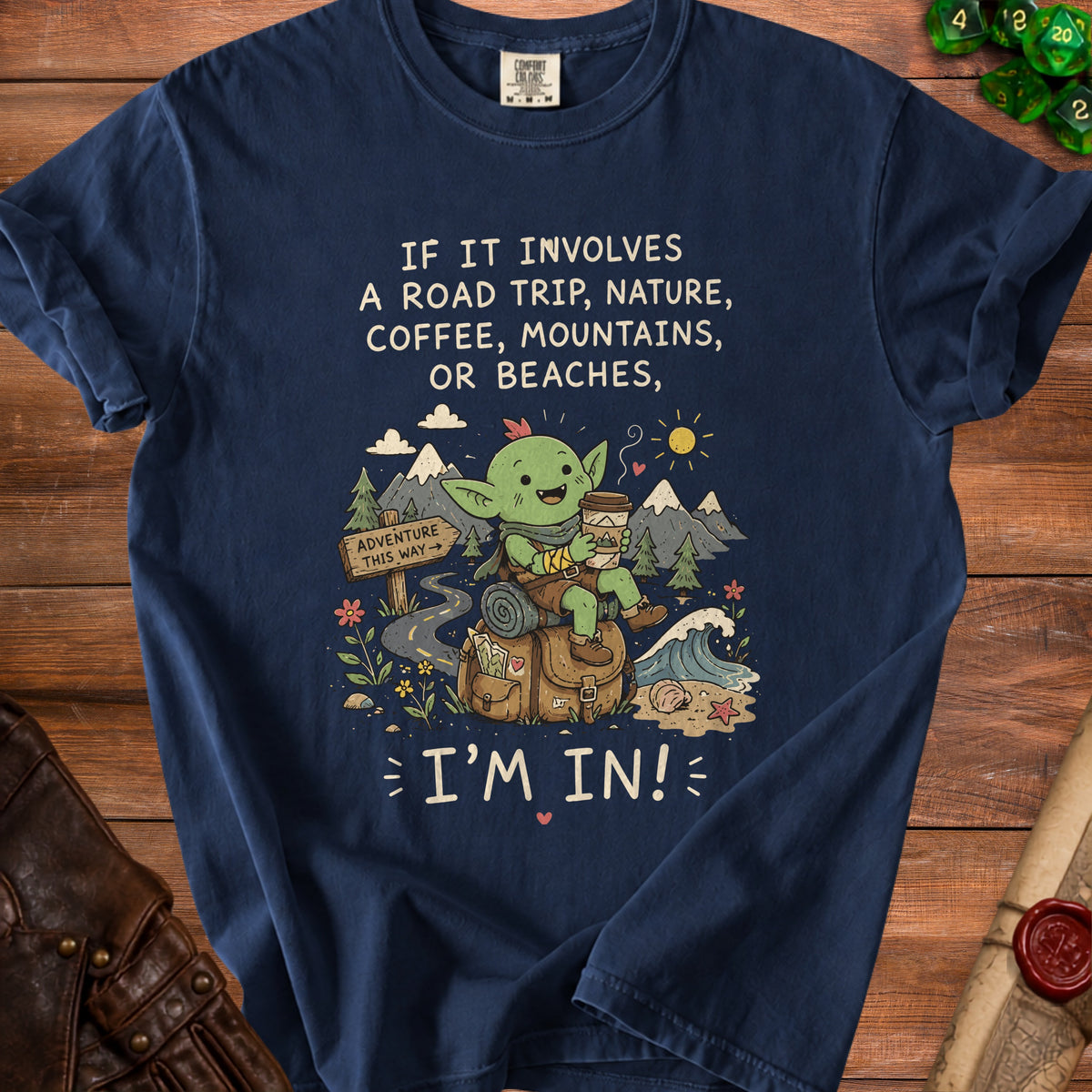 Navy t-shirt with a cartoon goblin holding coffee, saying "If it involves a road trip, nature, coffee, mountains, or beaches, I'm in!"