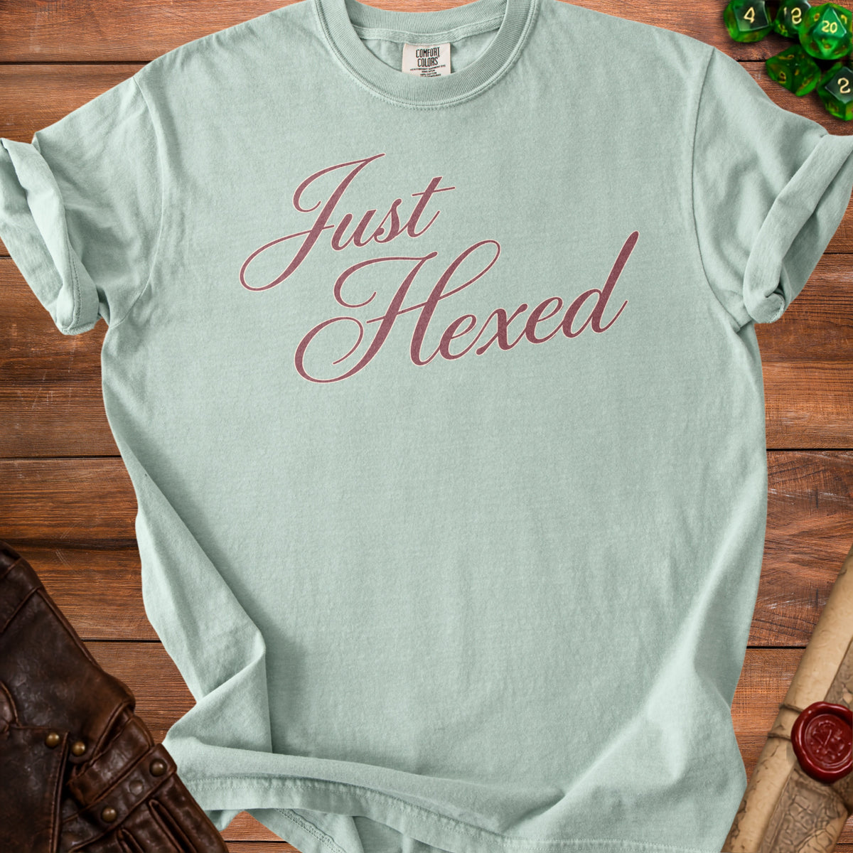Light green t-shirt with "Just Hexed" in dusty rose script.