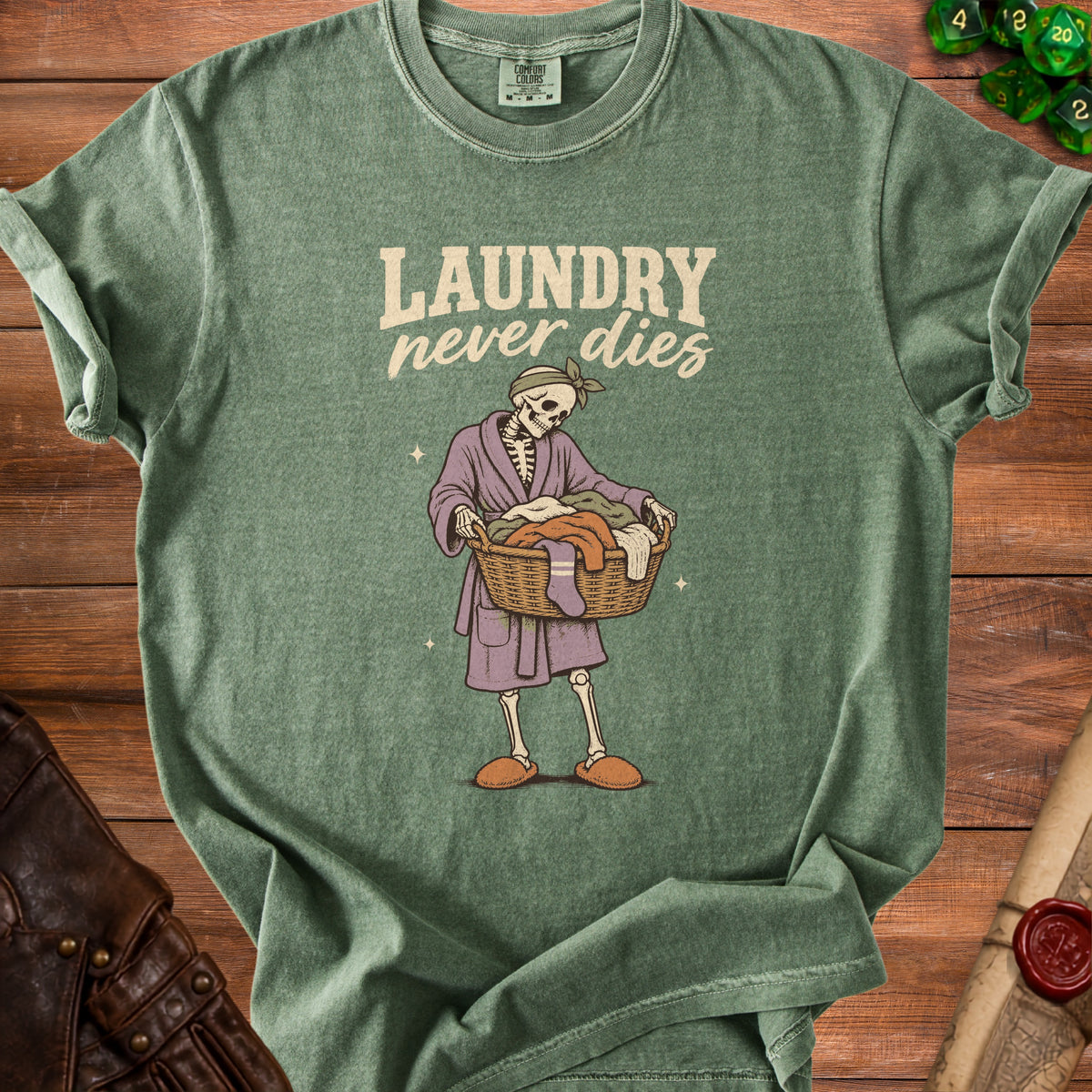 Green t-shirt with skeleton in robe carrying laundry basket and text "Laundry never dies".