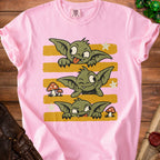 Pink t-shirt with three cartoon goblins peeking over yellow and pink stripes.